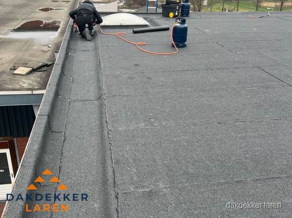 Dakdekker repareert bitumen dakbedekking op groot plat dak in Laren Dakdekker repareert bitumen dakbedekking op groot plat dak in Laren